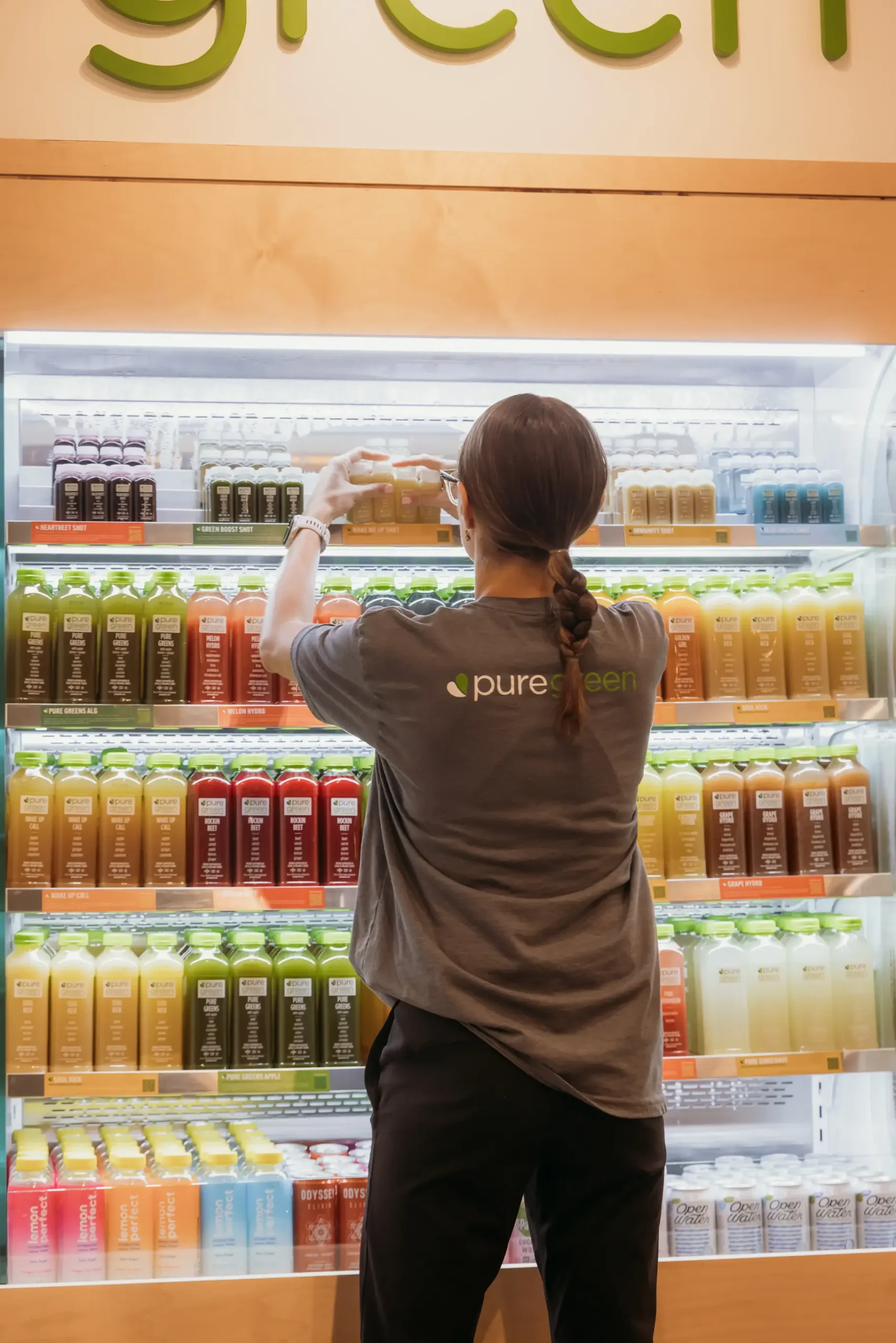 Pure Green juice bar crew arranging products on juice fridge